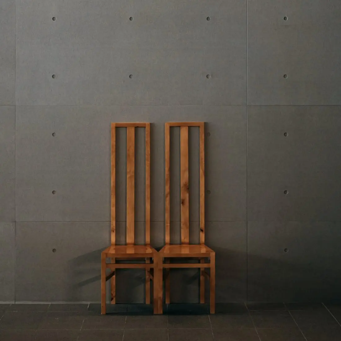 Detail of two timber chairs against concrete