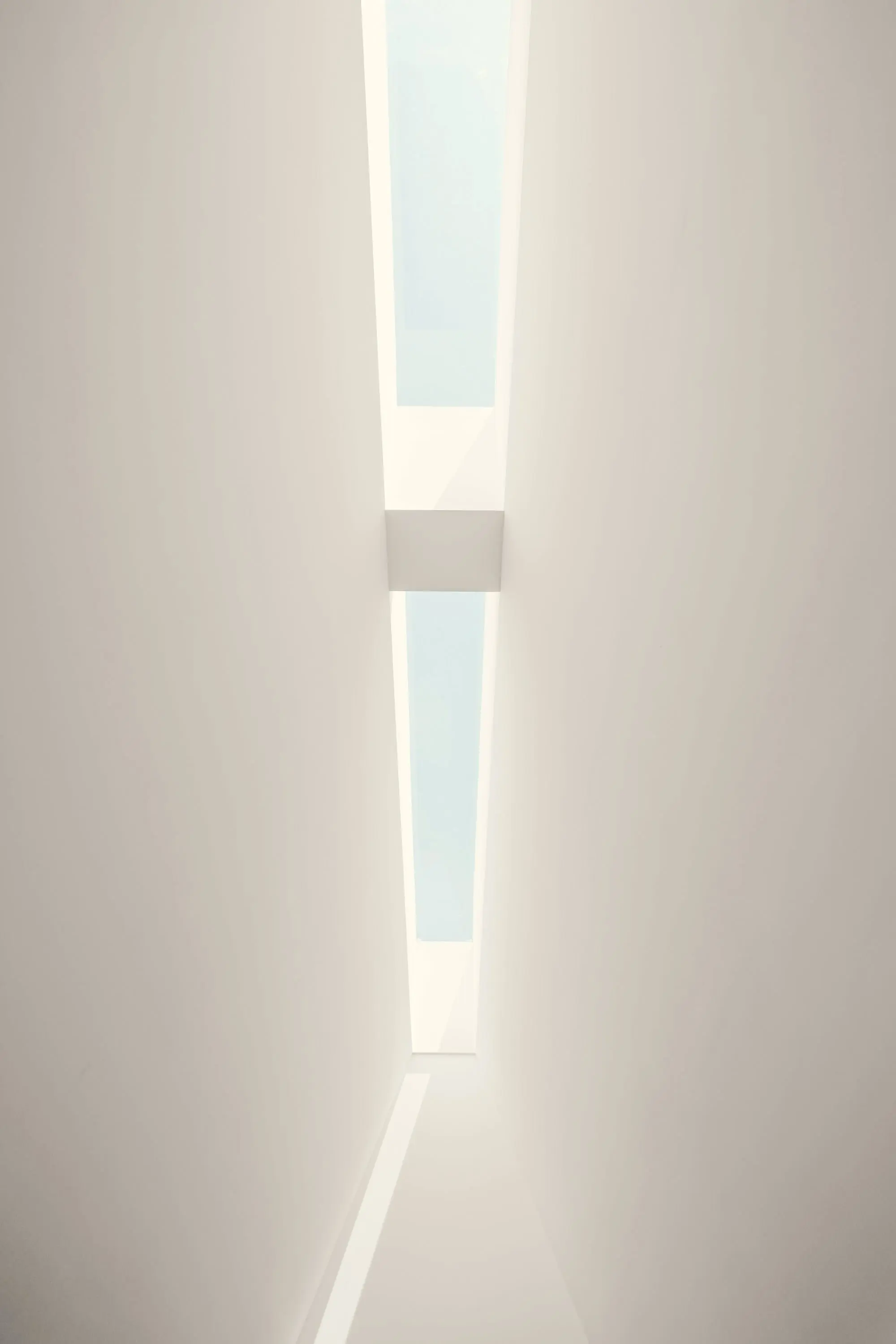 White wall with a single narrow vertical opening to the sky