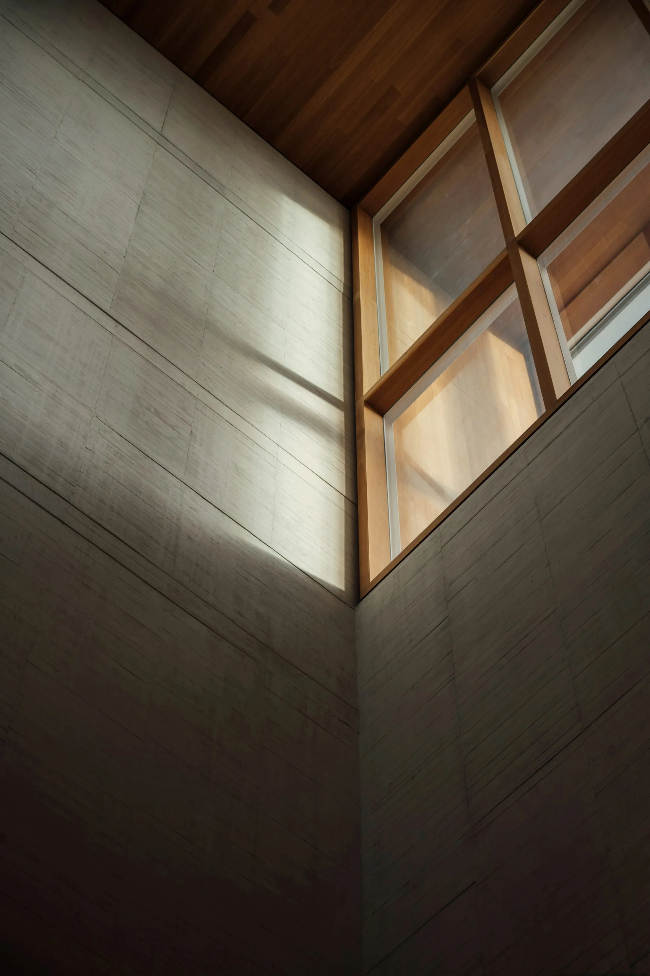 Daylight across a rough plaster wall beneath a timber-framed window
